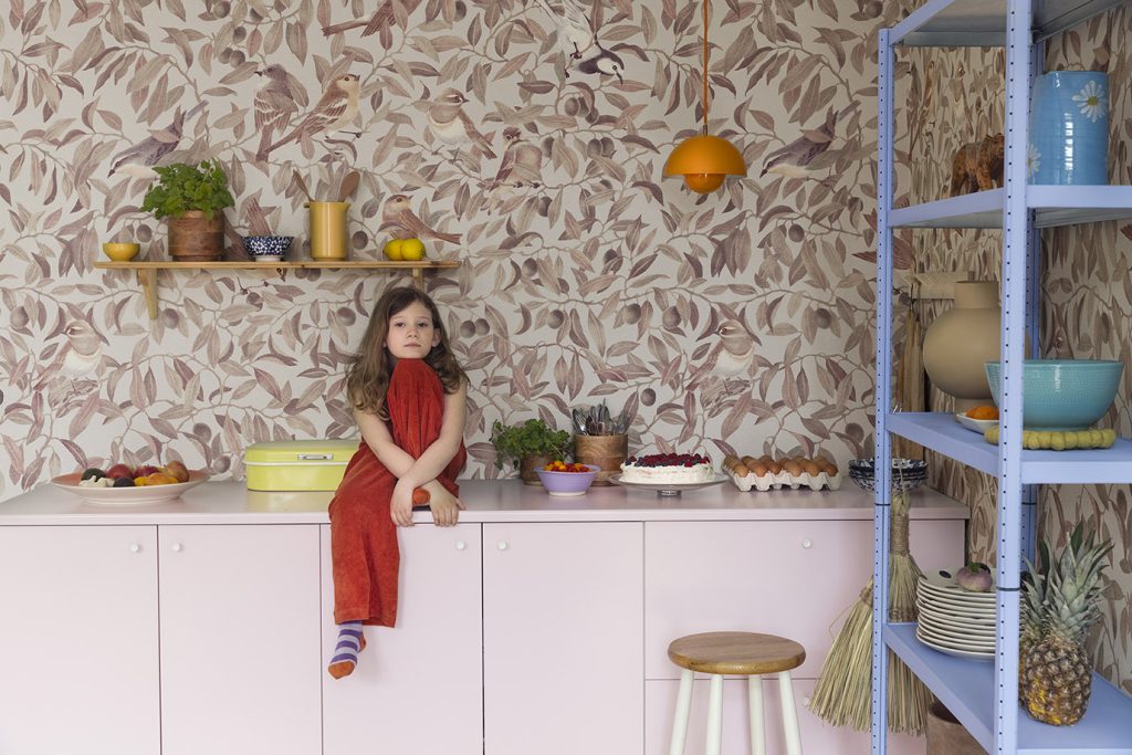 Girl sitting on counter with bird wallpaper in background